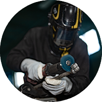 Un homme qui est entrain de polir un pièce en métal.